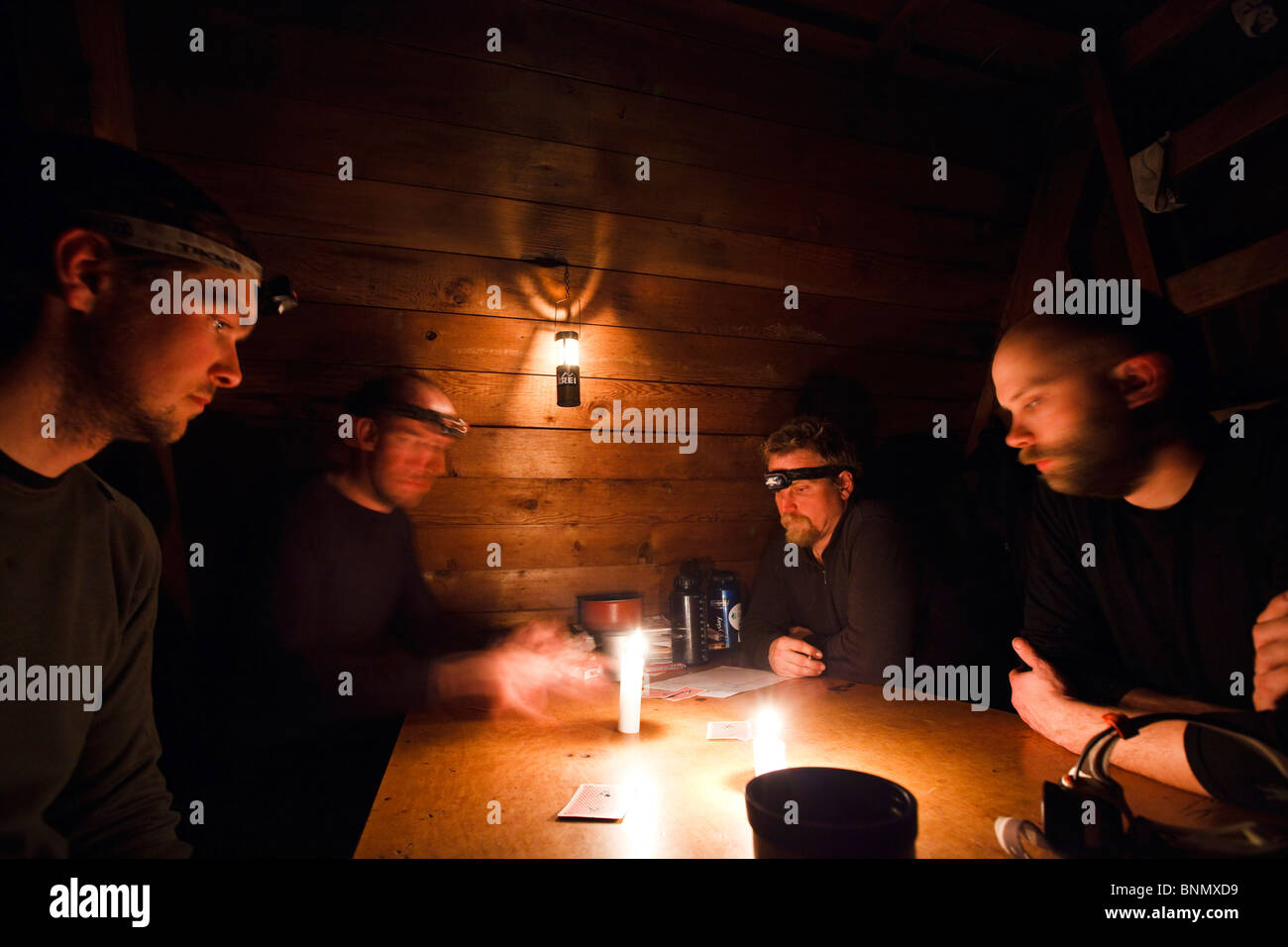 Gli uomini giocano cribbage a lume di candela nella foresta del servizio cabina Rynda vicino Andrews Creek, Stikine-LeConte deserto, Alaska Foto Stock