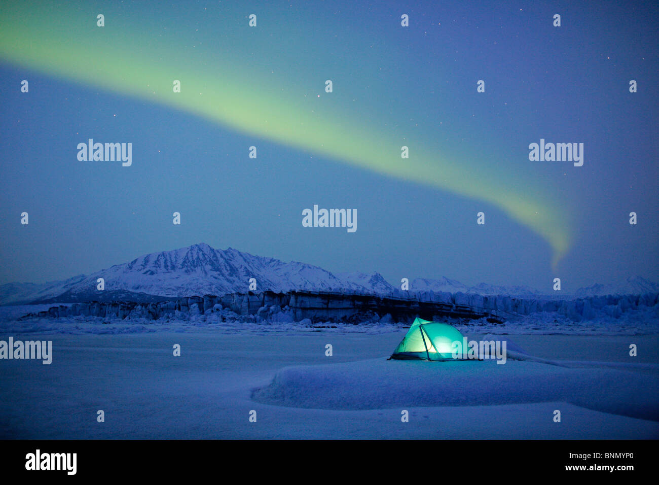 Luci del nord sulla tenda illuminata sul ghiacciaio Knik, Alaska, inverno Foto Stock