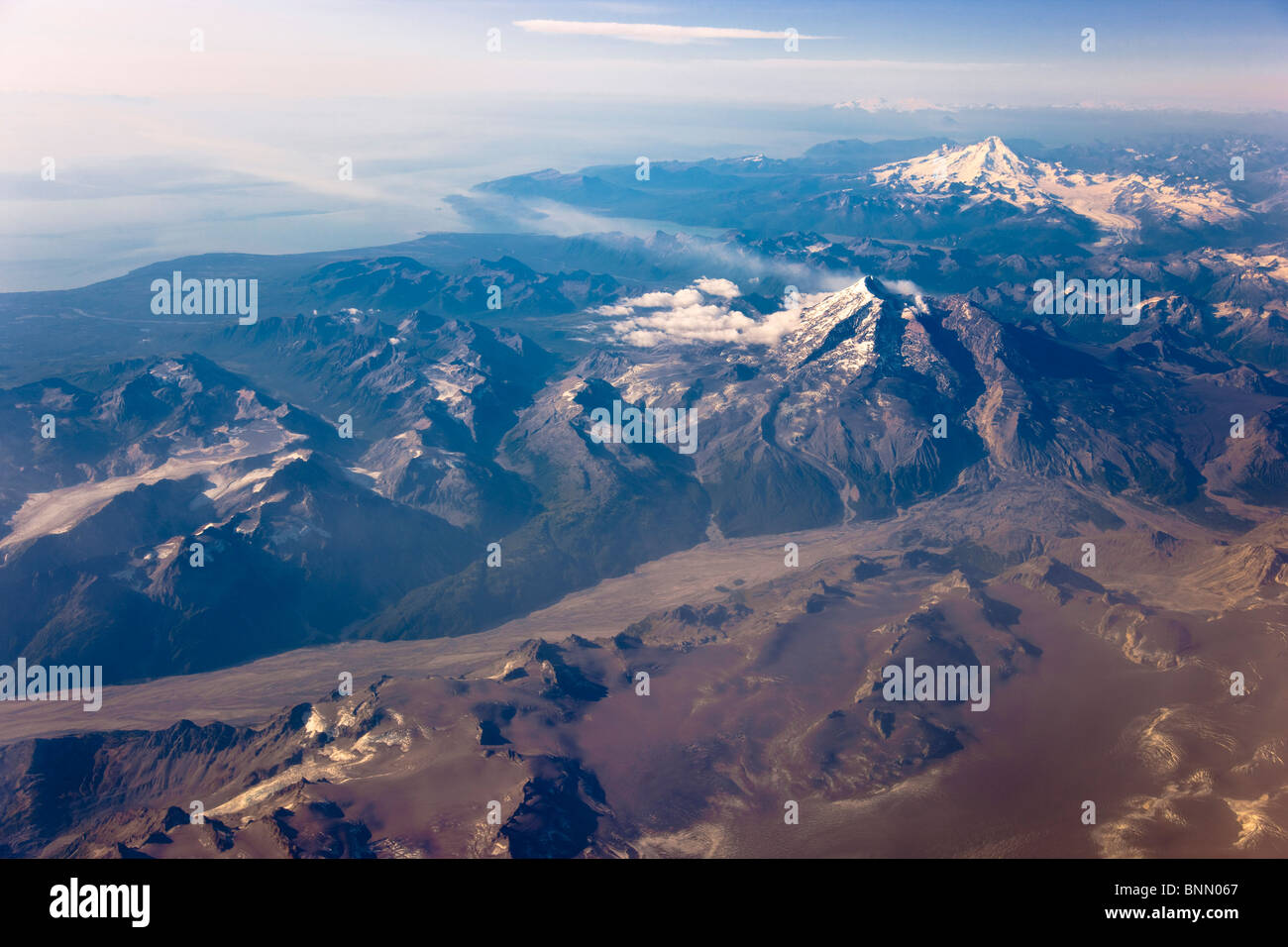 Vista Aerea del Mt. Redoubt con vapore ascendente dal cratere, ceneri vulcaniche sul ghiacciaio e Mt. Iliamna in distanza, Alaska Foto Stock