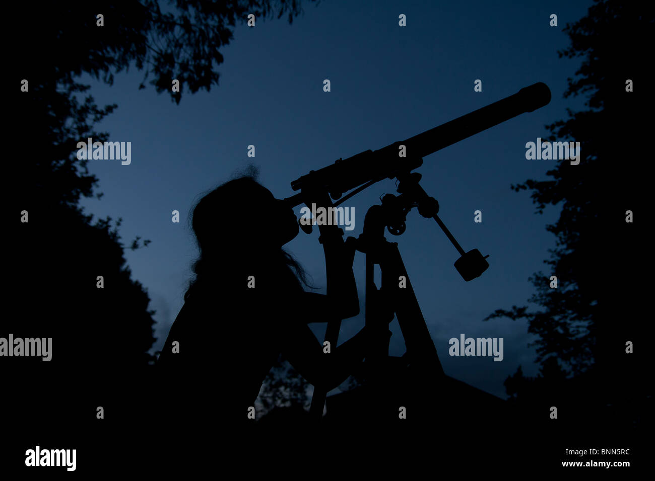 Ragazza guardando attraverso il telescopio Foto Stock