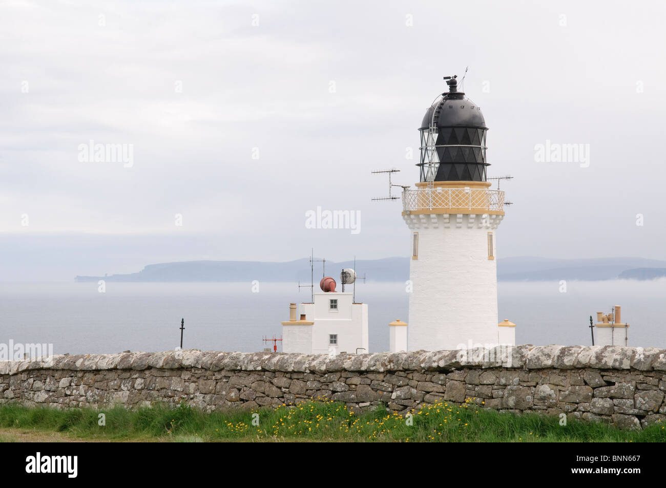 Il faro di Dunnett Testa, Scozia, con Orkney in distanza. La più settentrionale luogo sul continente BRITANNICO. Foto Stock