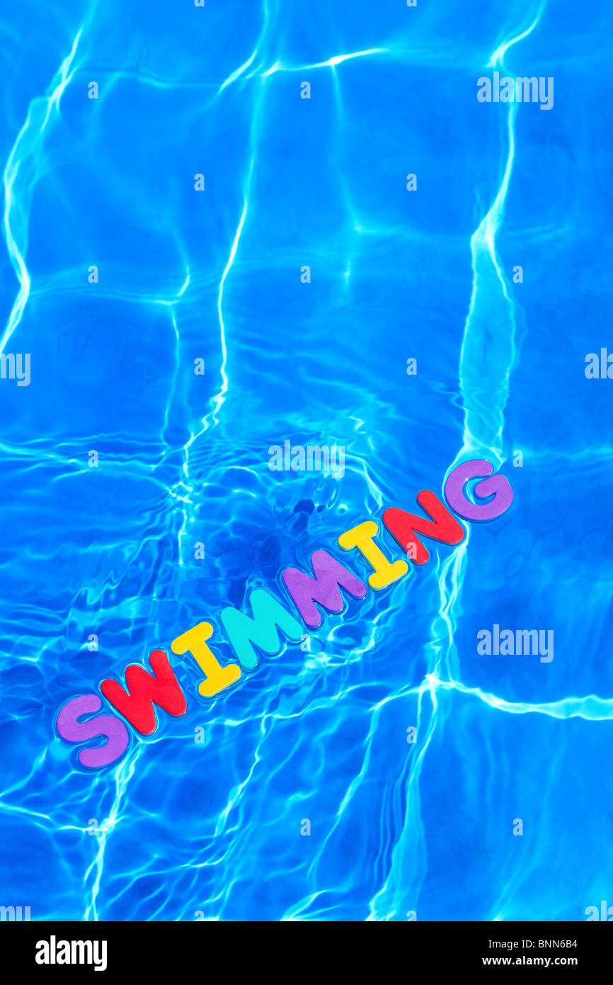 La parola nuoto di schiuma lettere galleggianti sulla superficie dell'acqua di piscina Foto Stock