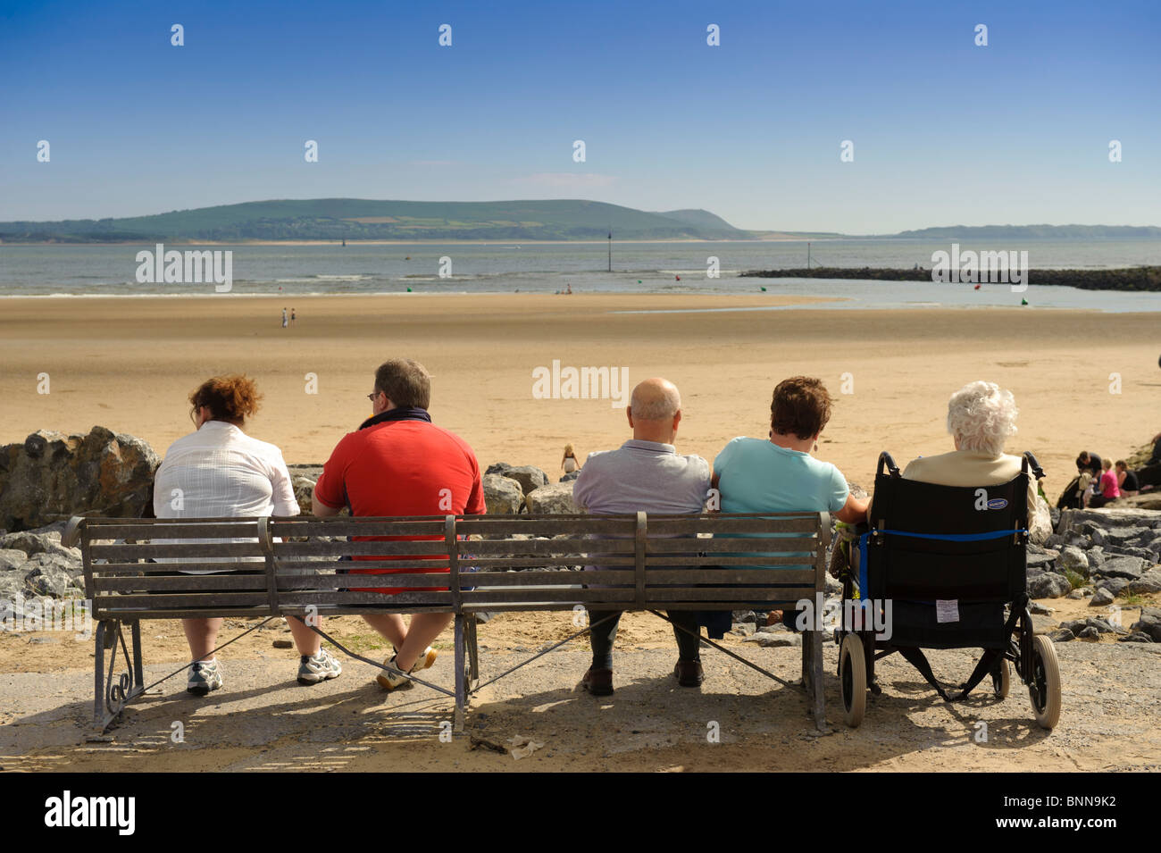 La gente seduta su una panchina di mare al Millennium parco costiero, Burry Port, Carmarthenshire South Wales UK Foto Stock