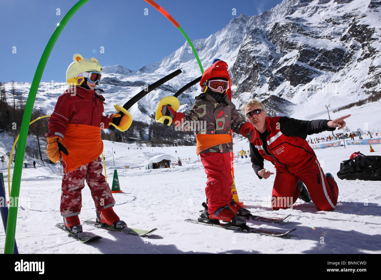 Svizzera Svizzera di Sport invernale Scuola di Sci bambini due maestri di sci Saas Fee Vallese sci sci Per saperne di casco mostra spiegare Foto Stock