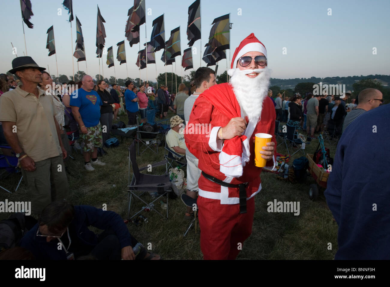 Glastonbury Festival. Uomo vestito in costume come costume di Babbo Natale / Santa Claus in una folla. Foto Stock