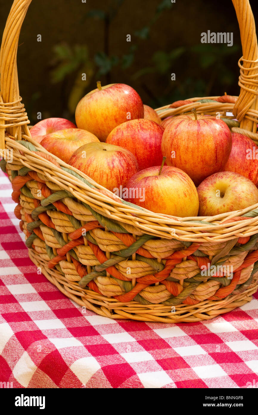 Cesto con mele rosse sul tavolo con rosso Gingham tovaglia Foto Stock