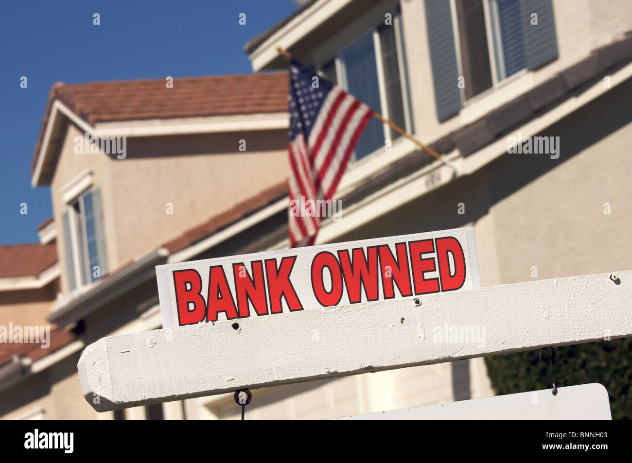 Banca di proprietà immobiliare di segno e la casa con la bandiera americana in background. Foto Stock
