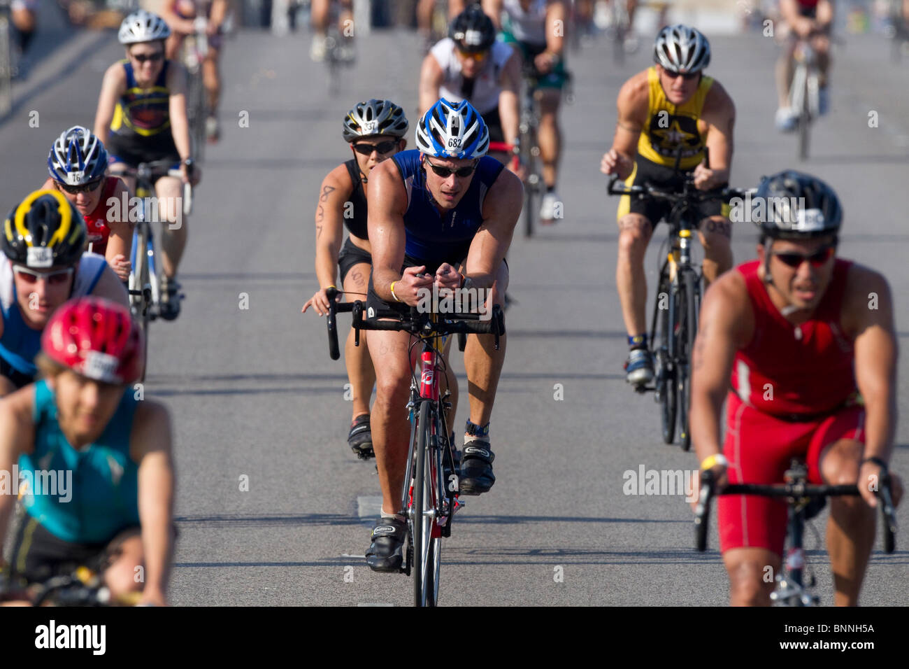 I concorrenti nella seconda gamba di un pedale di triathlon le loro biciclette attraverso un ponte nel centro di Austin, Texas. Foto Stock
