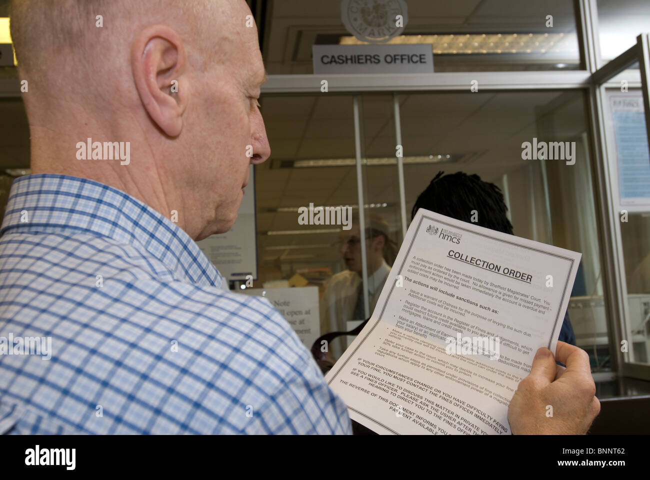 Uomo con ordine di raccolta in attesa di pagare una multa a magistrati corte cassieri Office. Foto Stock