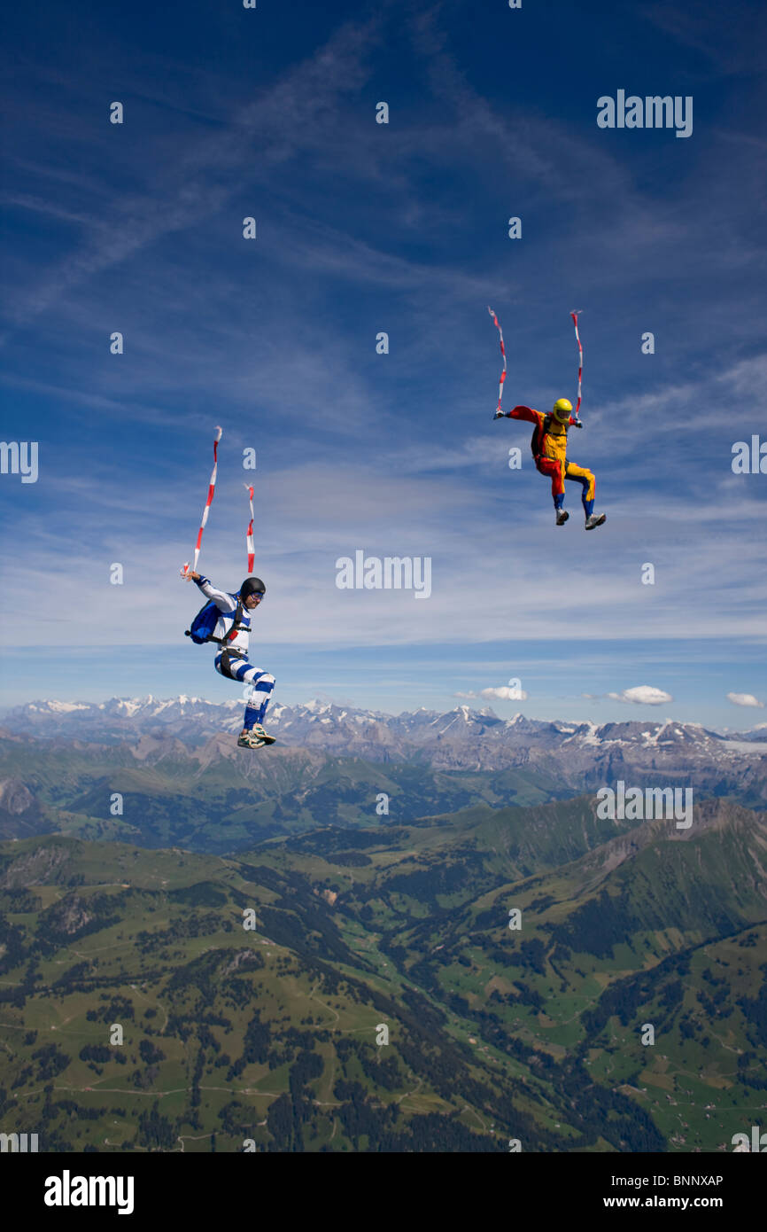 Skydivers sono battenti testa fino all'interno di un team in sit fly posizione su uno spettacolare paesaggio di montagna con oltre 120 mph velocità. Foto Stock