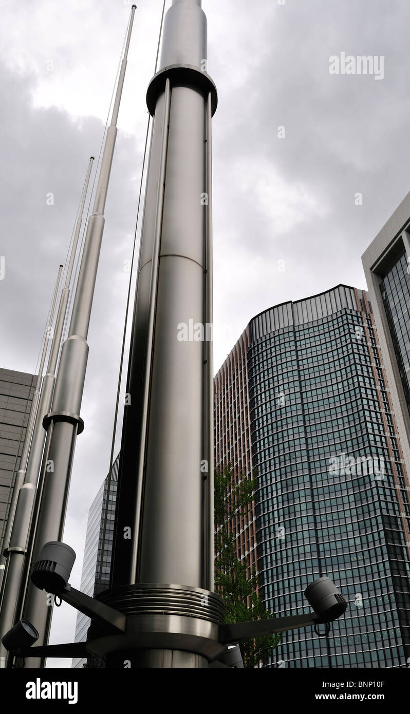 Shiny bandiera pali con alti edifici in background contro il cielo nuvoloso (Tokyo, Giappone) Foto Stock