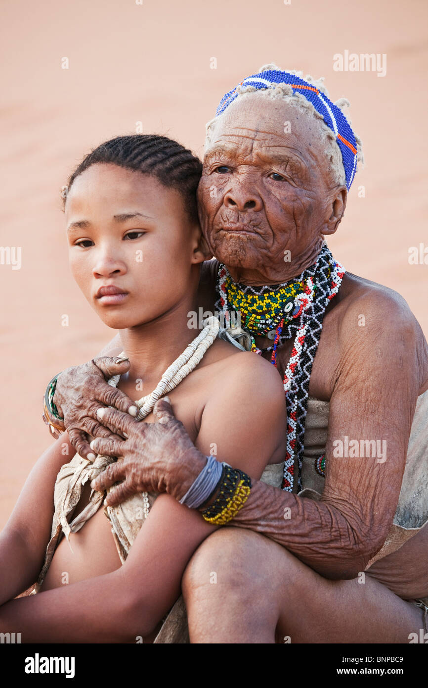 Bushman/San persone. Ragazza giovane con la vecchia donna abbracciando Foto Stock