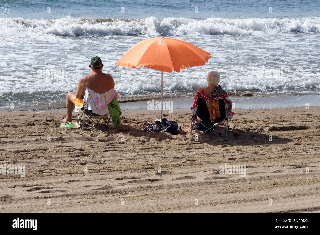 2 vacanzieri seduti sulle sedie a sdraio sulla spiaggia con ombrellone a Puerto de Mazarron MURCIA Costa Calida Spagna Europa Foto Stock