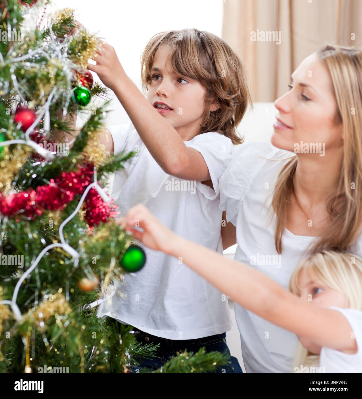 Bambini Appendere le decorazioni di Natale con la loro madre Foto Stock