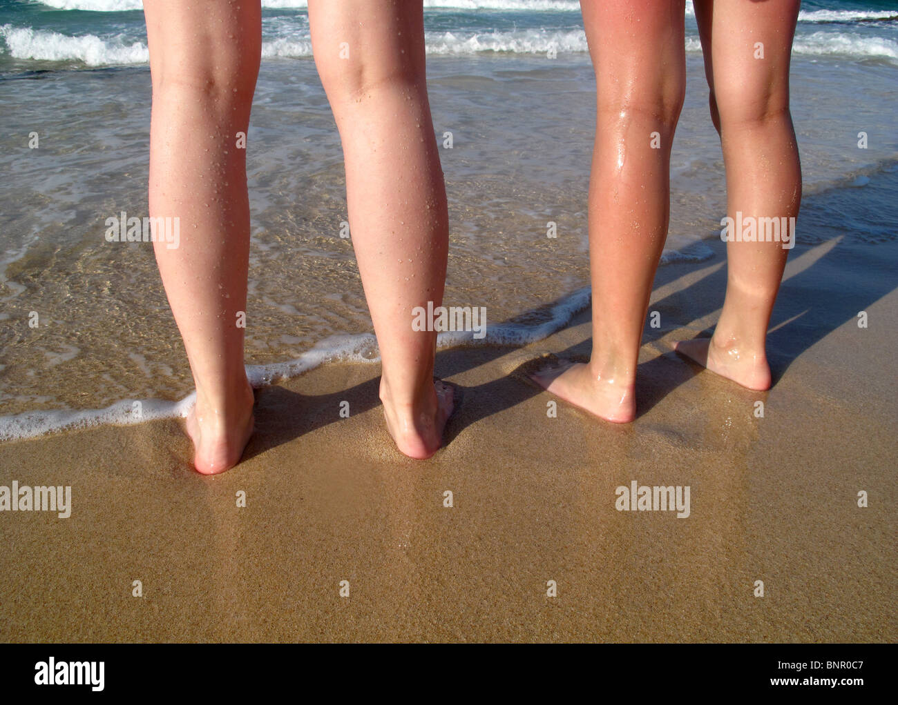 Le giovani ragazze piedi paddling in bordo di mare Foto stock - Alamy