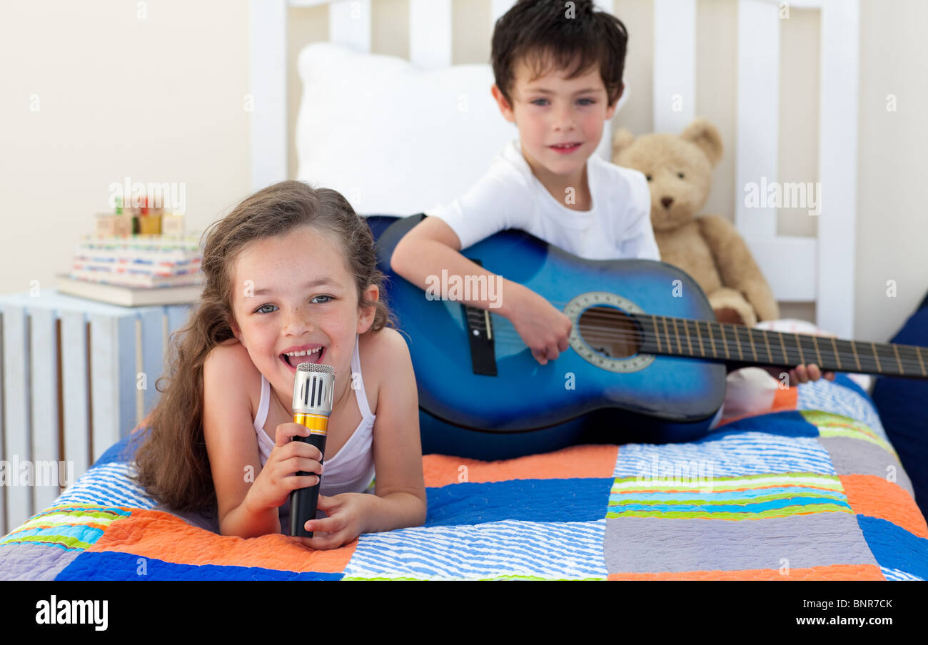 Little Boy a suonare la chitarra e sua sorella canti Foto stock - Alamy