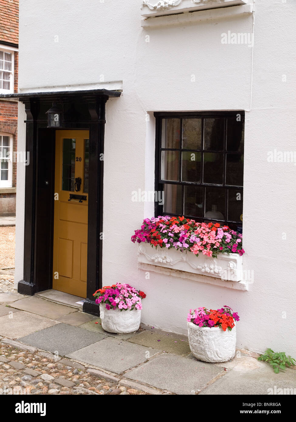 Un piccolo dipinto di bianco di casa con colorati window box e vasi di fiori nella piazza della chiesa la segala East Sussex Foto Stock