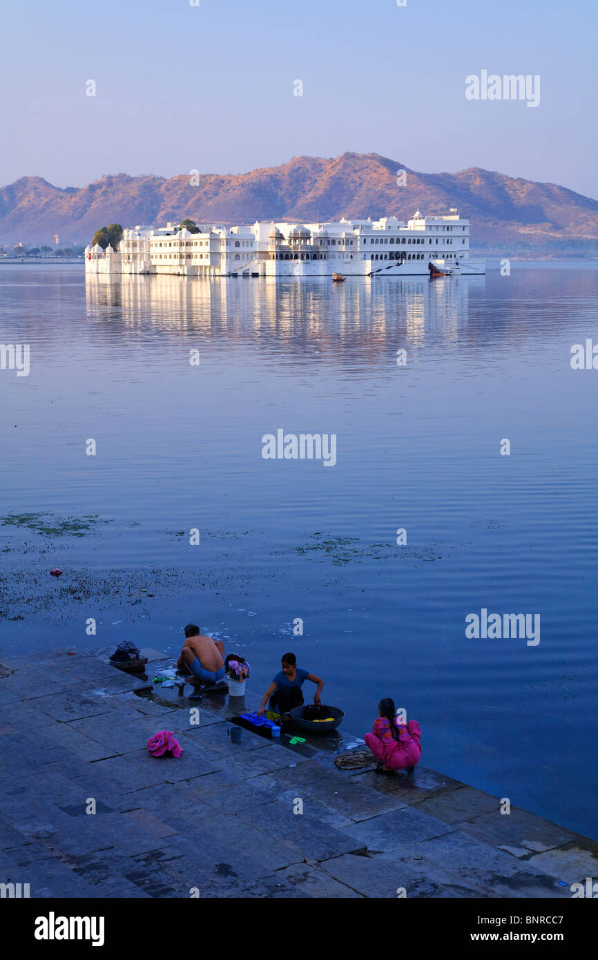 India - Rajasthan - Udaipur - il lavaggio della biancheria nel lago Pichola con il Lago Palace Hotel in background Foto Stock