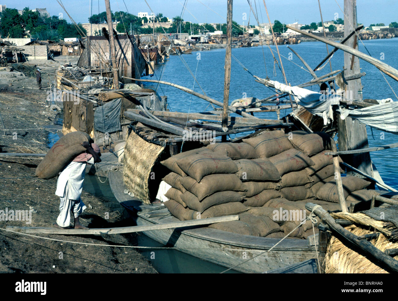 Uomo che carica una barca con sacchi di fertilser a Sukkur, Indo River, Pakistan Foto Stock