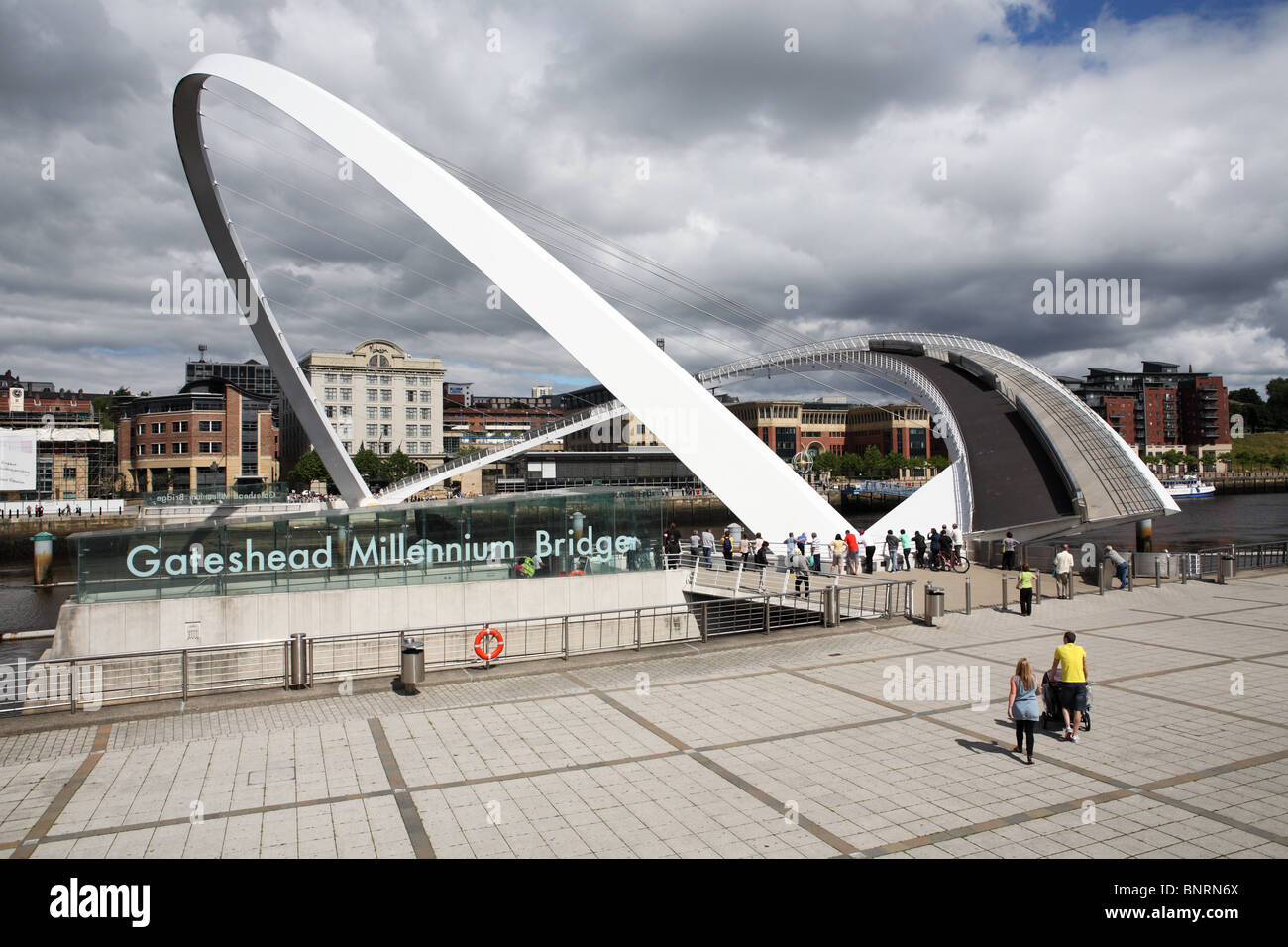 Spettatori guarda il Gateshead Millennium Bridge apertura sul fiume Tyne, visto da di Gateshead, England, Regno Unito Foto Stock