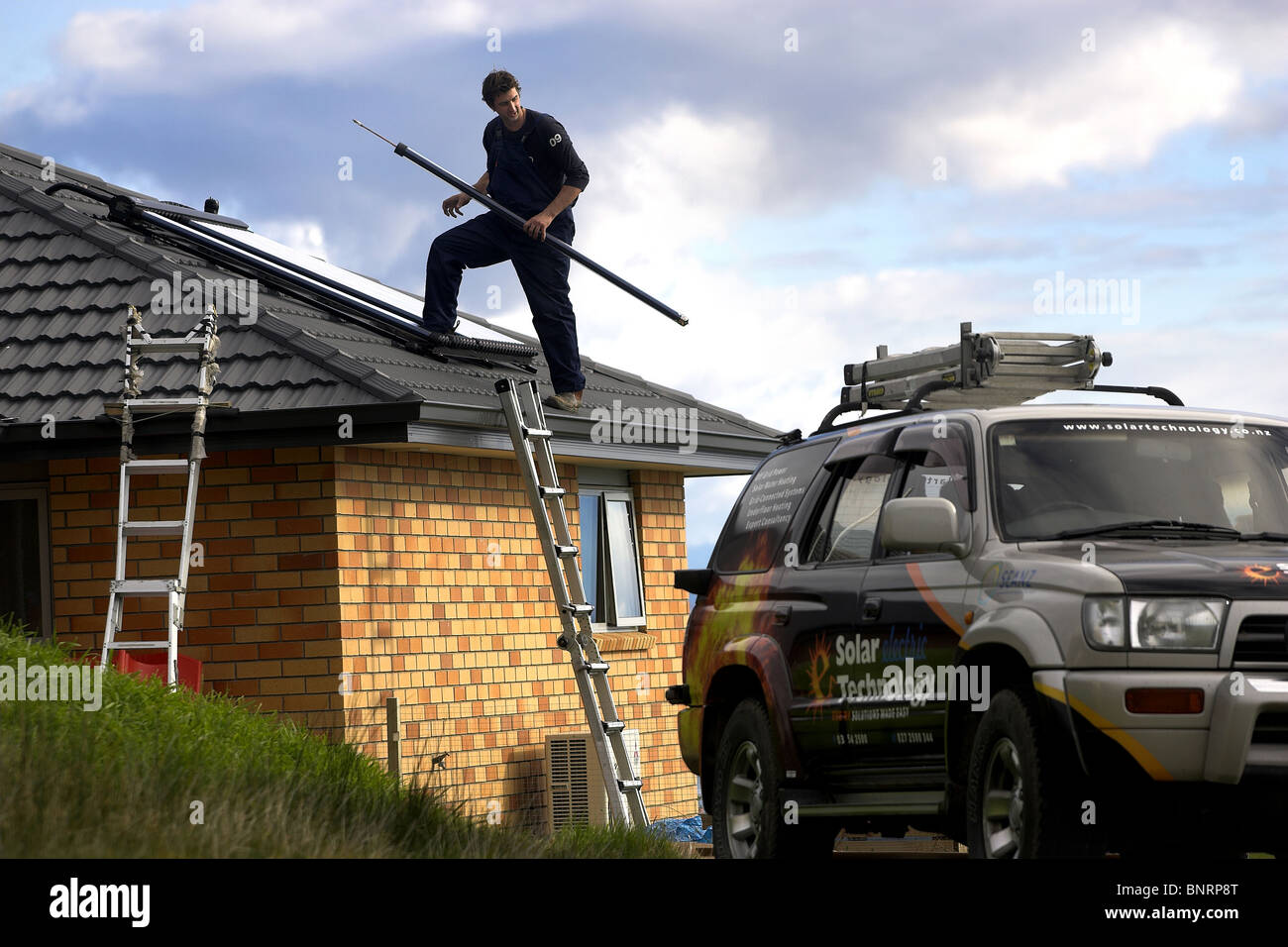 Artigiano qualificato installazione solare di acqua calda sistema a una casa, Nelson, Nuova Zelanda, la città con la più alta ore di sole Foto Stock