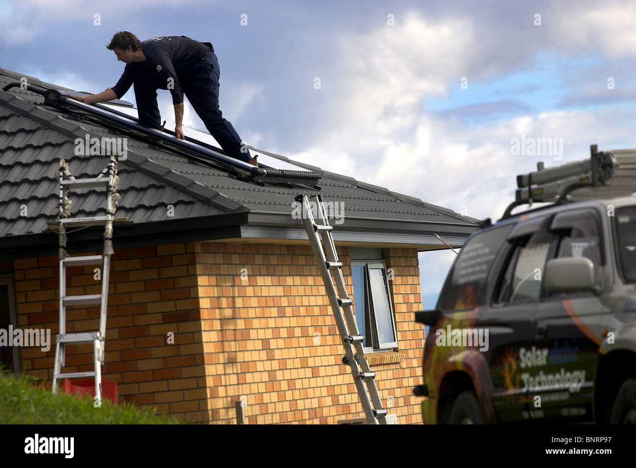 Artigiano qualificato installazione solare di acqua calda sistema a una casa, Nelson, Nuova Zelanda, la città con la più alta ore di sole Foto Stock