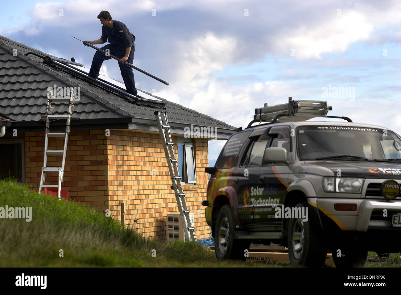 Artigiano qualificato installazione solare di acqua calda sistema a una casa, Nelson, Nuova Zelanda, la città con la più alta ore di sole Foto Stock