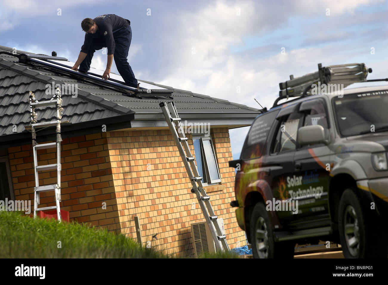 Artigiano qualificato installazione solare di acqua calda sistema a una casa, Nelson, Nuova Zelanda, la città con la più alta ore di sole Foto Stock