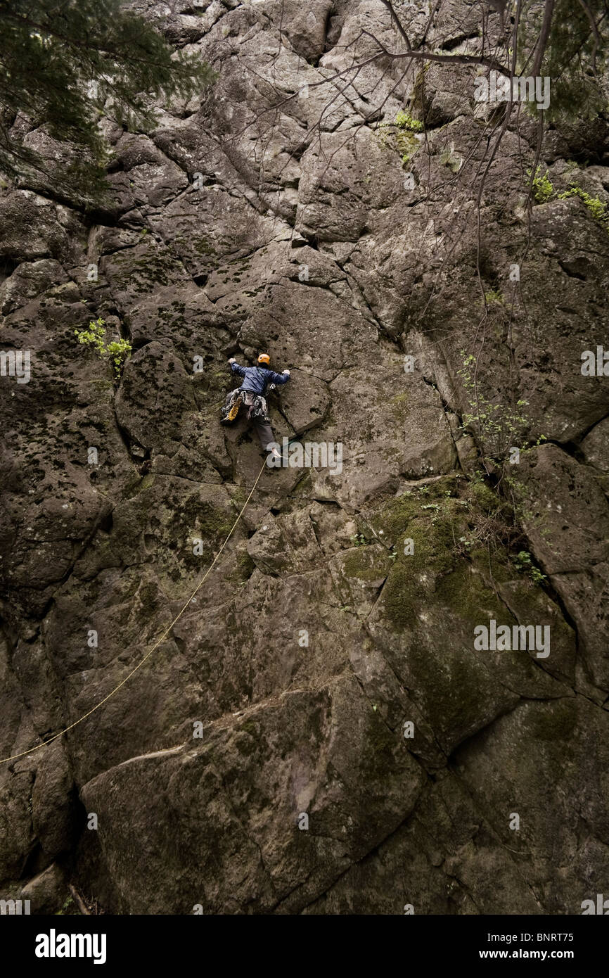 Un scalatore di piombo la scalabilità di una roccia. Foto Stock