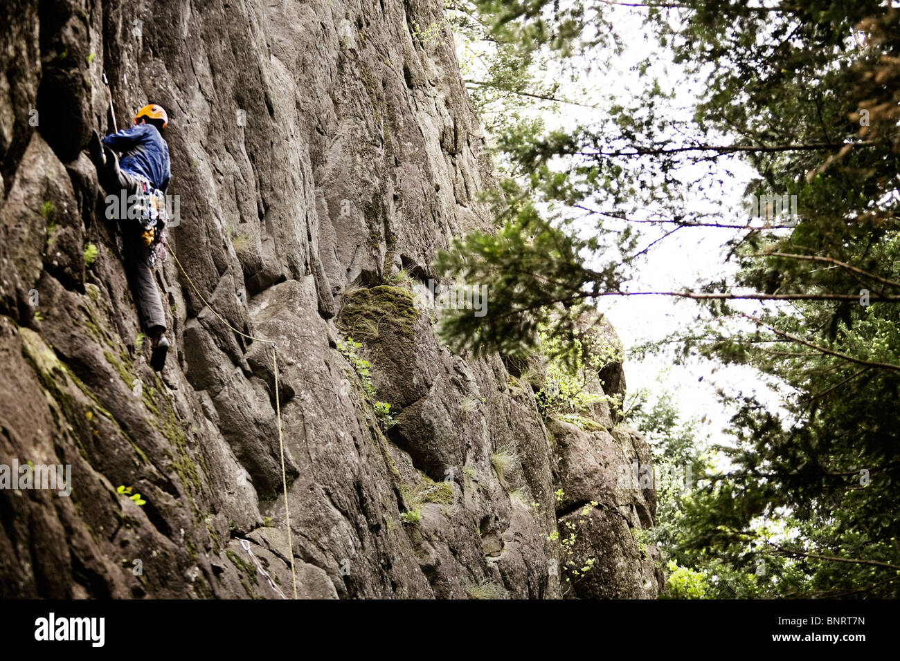 Un scalatore si appiattisce se stesso contro una roccia. Foto Stock