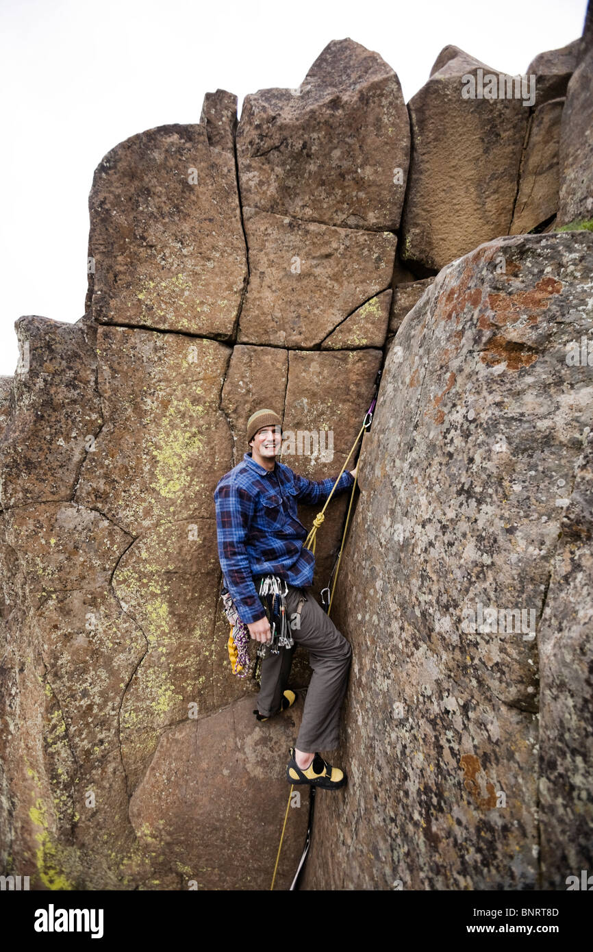 Un scalatore pause vicino alla parte superiore di una roccia rotta. Foto Stock