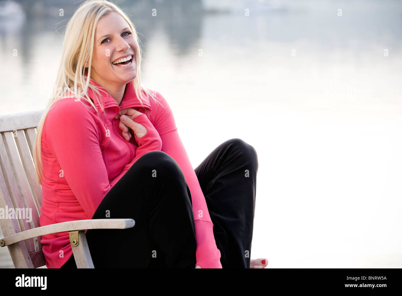 Una giovane donna appendere fuori su una dock sul lago Washington e sorridente alla fotocamera. Foto Stock