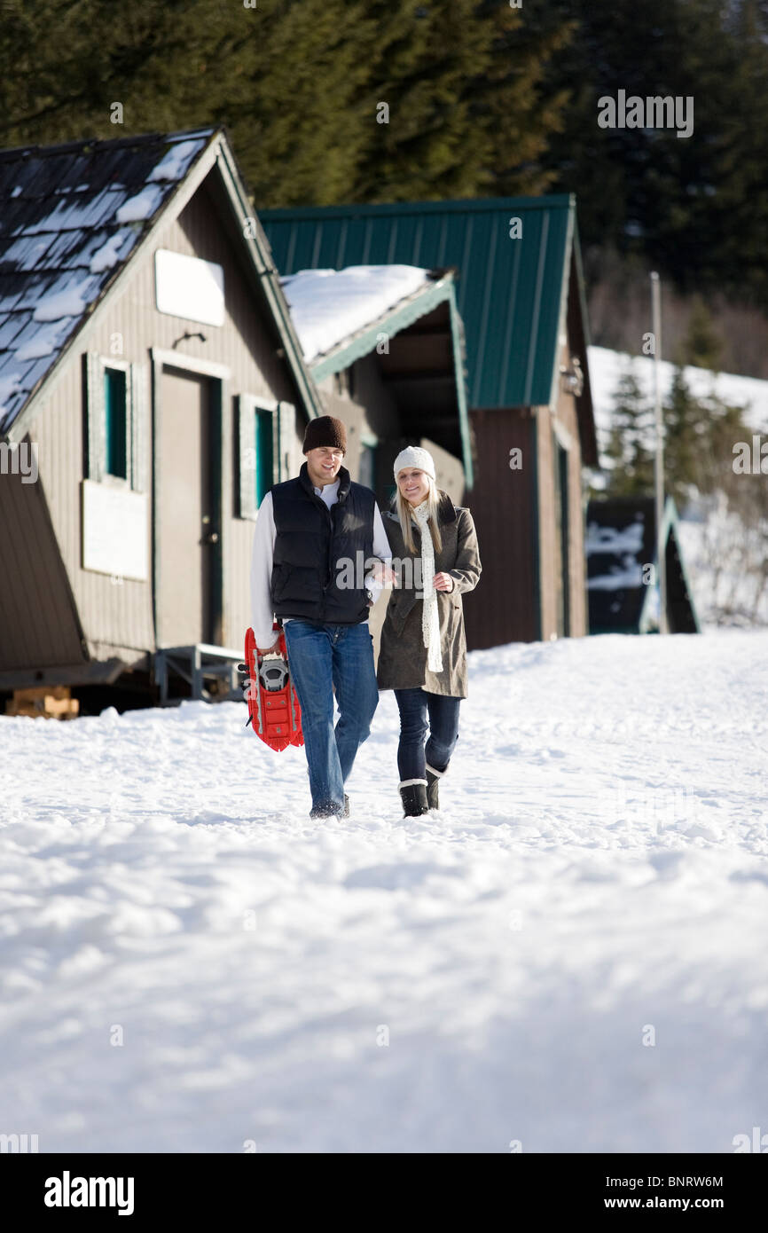 Un uomo e una donna godere di una giornata di snow shoeing attività in montagna. Foto Stock