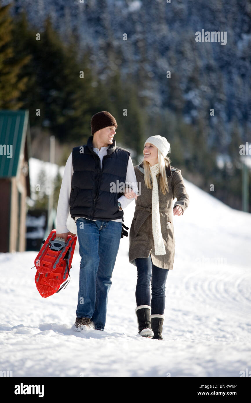 Un uomo e una donna godere di una giornata di snow shoeing attività in montagna. Foto Stock