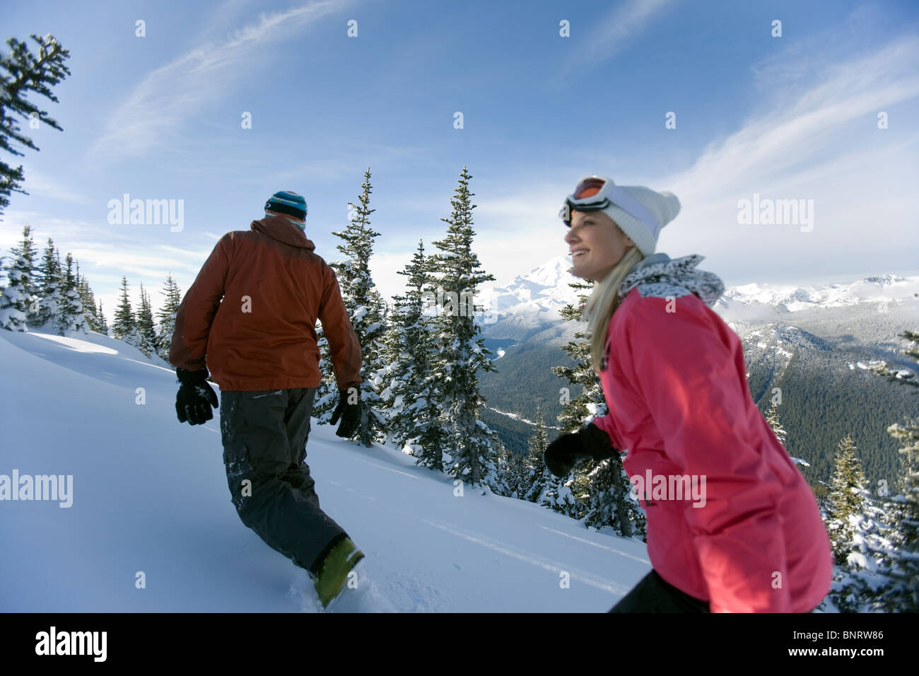 Un uomo e una donna escursione in marcia di sci attraverso la neve intatta con Mt. Rainier in background. Foto Stock