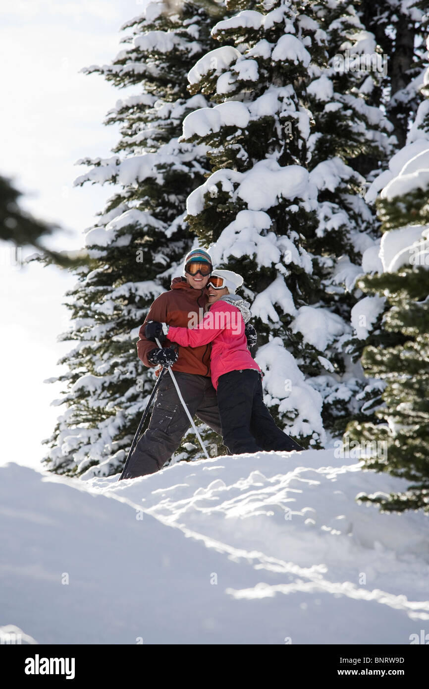 Una giovane coppia abbracciare e sorridere mentre godendo una giornata di sole sulle piste da sci. Foto Stock