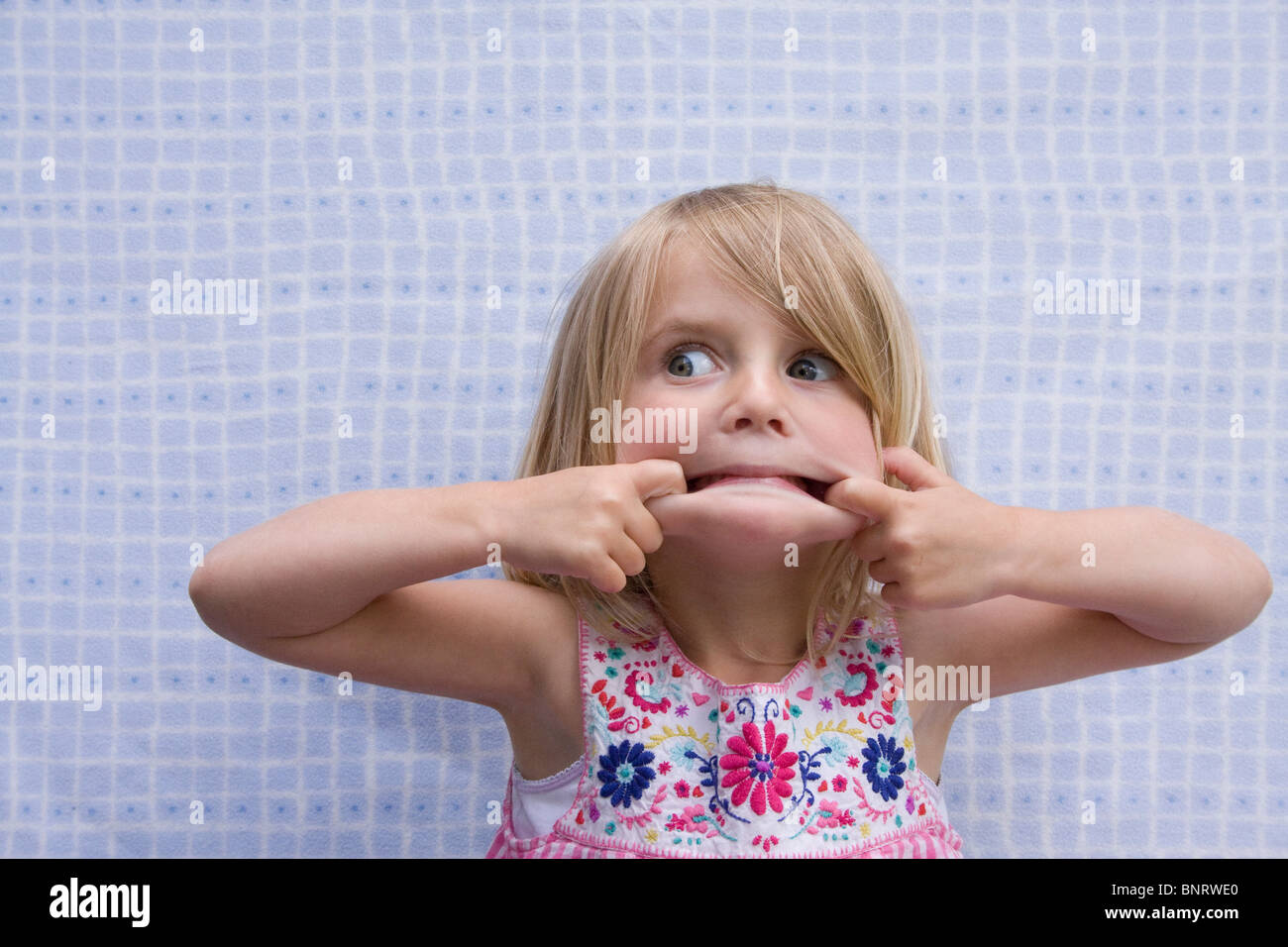 Bimba bionda facendo una faccia buffa. Foto Stock