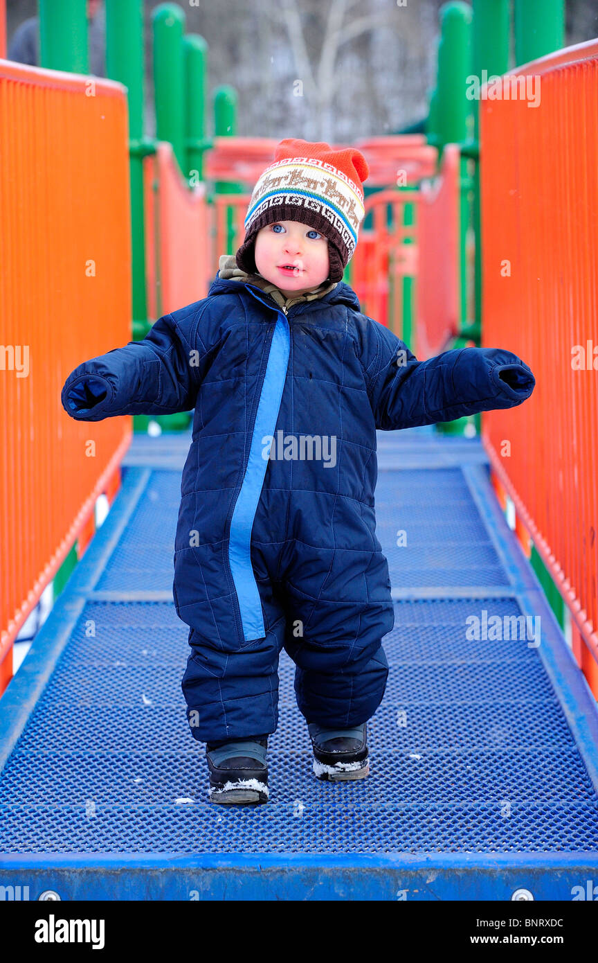 Bambino gioca sul parco giochi d'inverno. Foto Stock