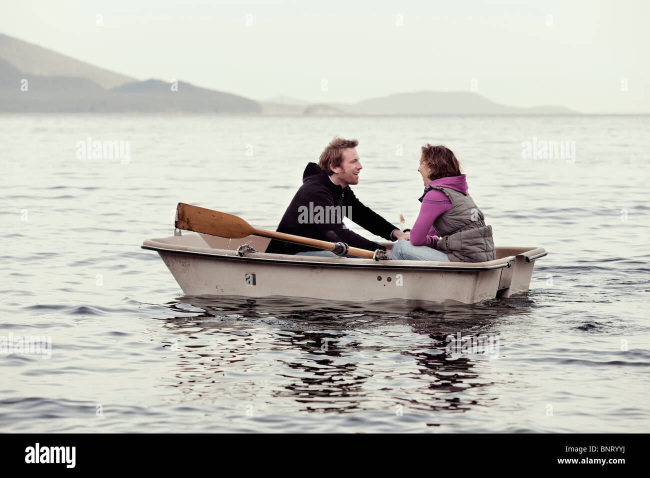 Una giovane coppia riga in Puget Sound da Orcas Island in una piccola barca a remi. Foto Stock