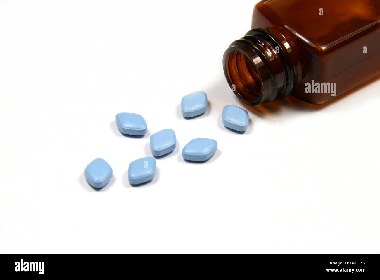Blu Viagra anti-impotenza compresse versata da una bottiglia su uno sfondo bianco. Foto Stock