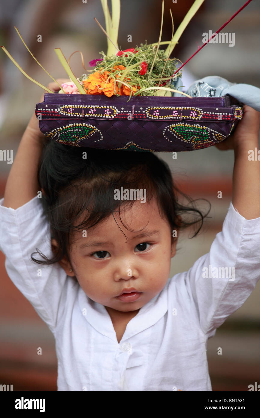 Indonesia, Bali, Galungan festival, cerimonia religiosa, bambino offerte di trasporto, Foto Stock