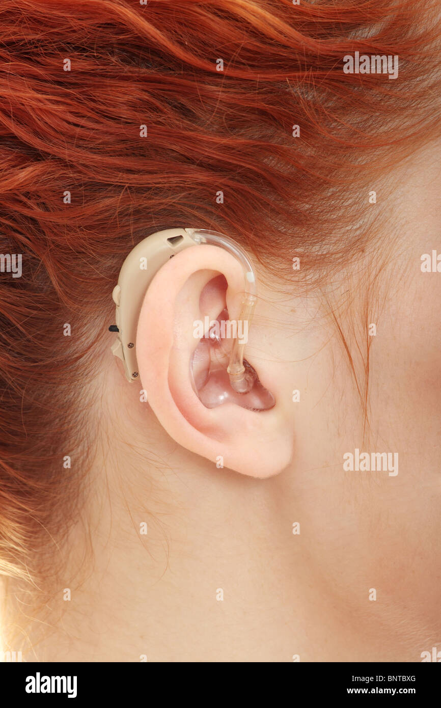 Redhead donna che indossa Hearing Aid Foto Stock