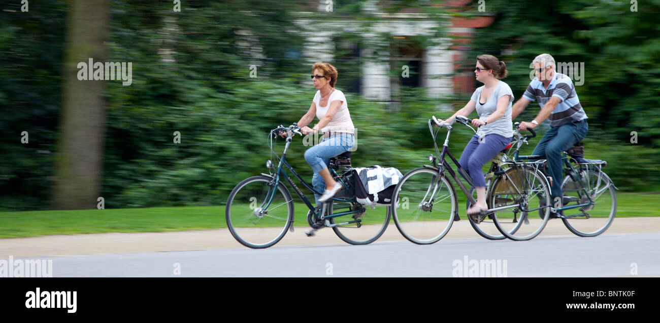 Immagine panoramica di 3 persone in bicicletta attraverso il parco della città. La fotocamera è stata eseguita una panoramica a leggermente la sfocatura dello sfondo Foto Stock