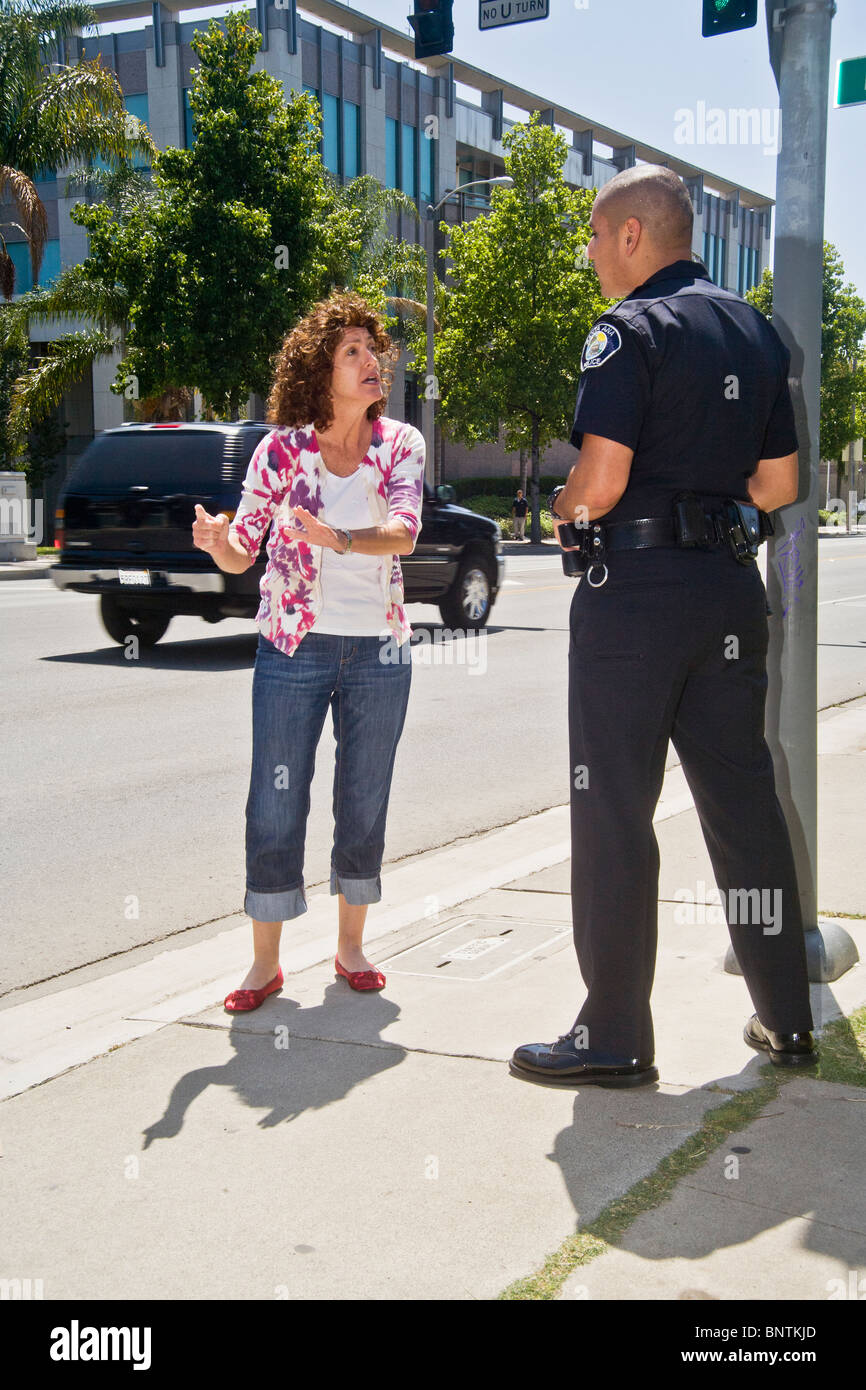 Una donna sostiene con un ispanico funzionario di polizia dopo essere stato fermato per una violazione del codice della strada in Santa Ana CA. Foto Stock