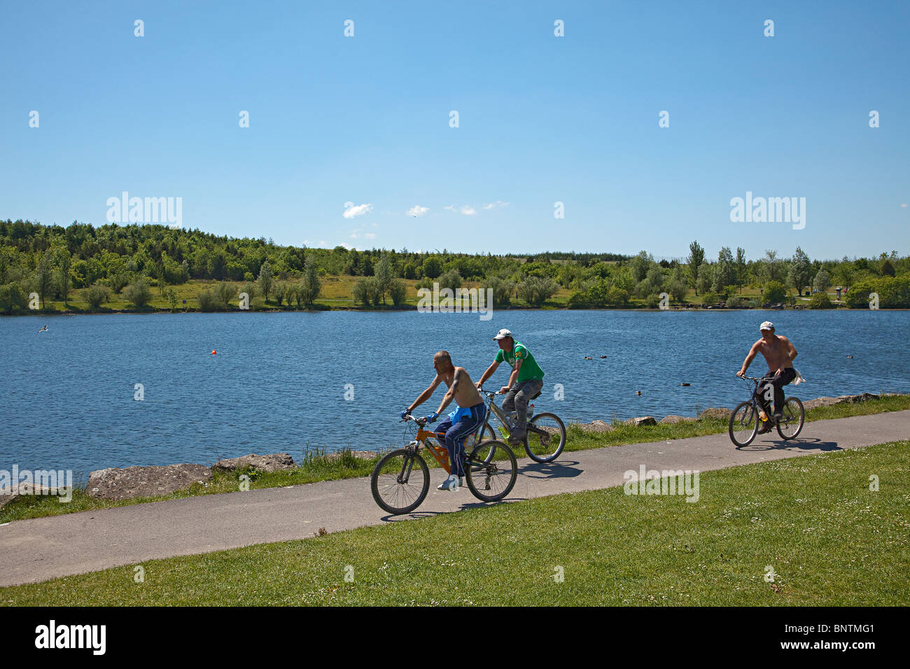 Tre uomini in bicicletta intorno al lago a Bryn Bach Country Park Tredegar Wales UK Foto Stock