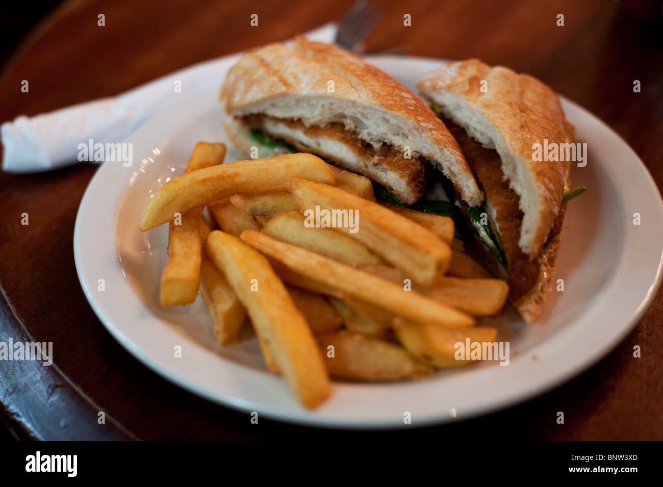 Un pollo fritto in sandwich di pane ciabatta servita con chip in corrispondenza di un tipico pub inglese a Londra. Foto Stock