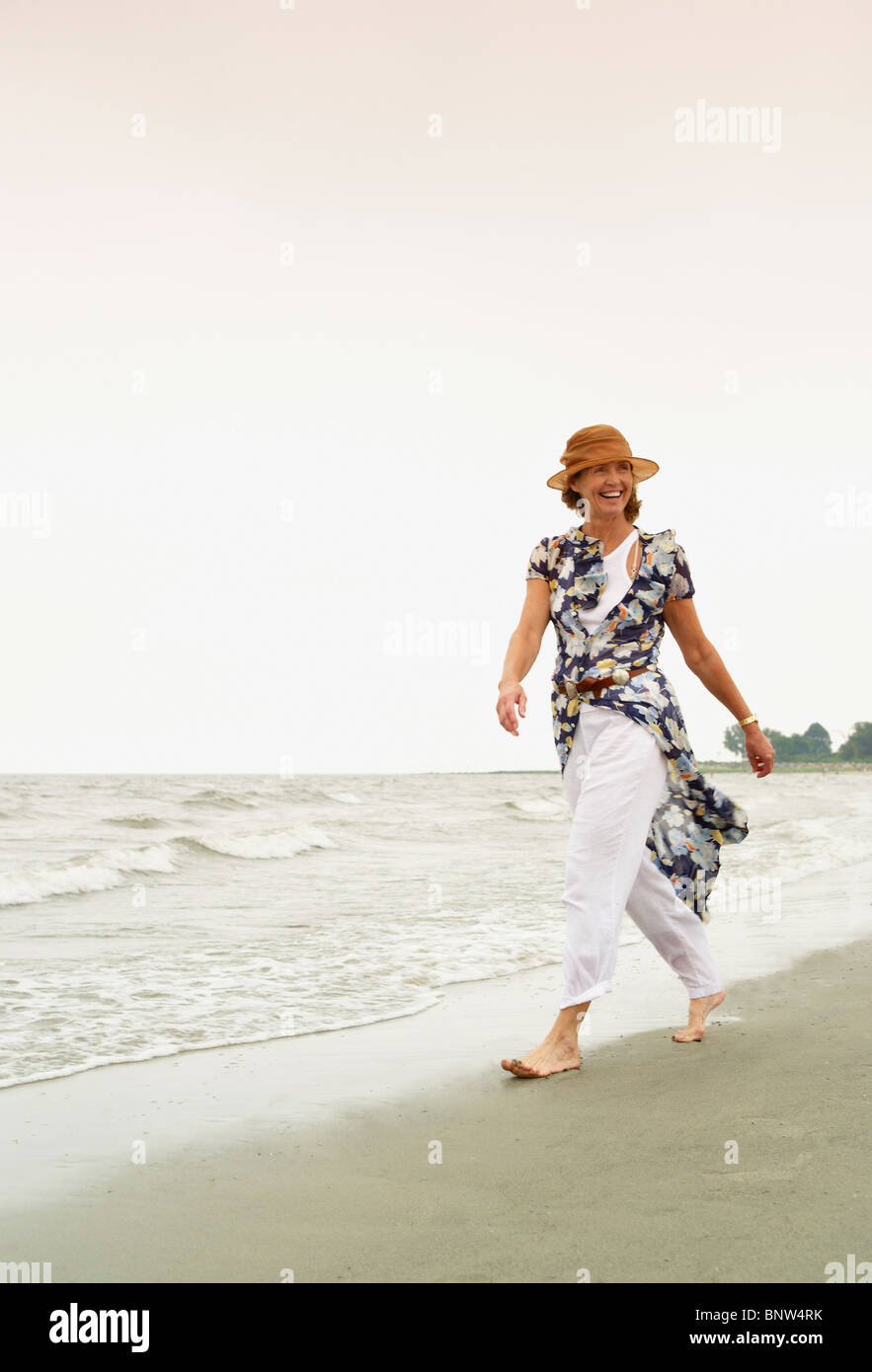 Donna di camminare sulla spiaggia Foto Stock