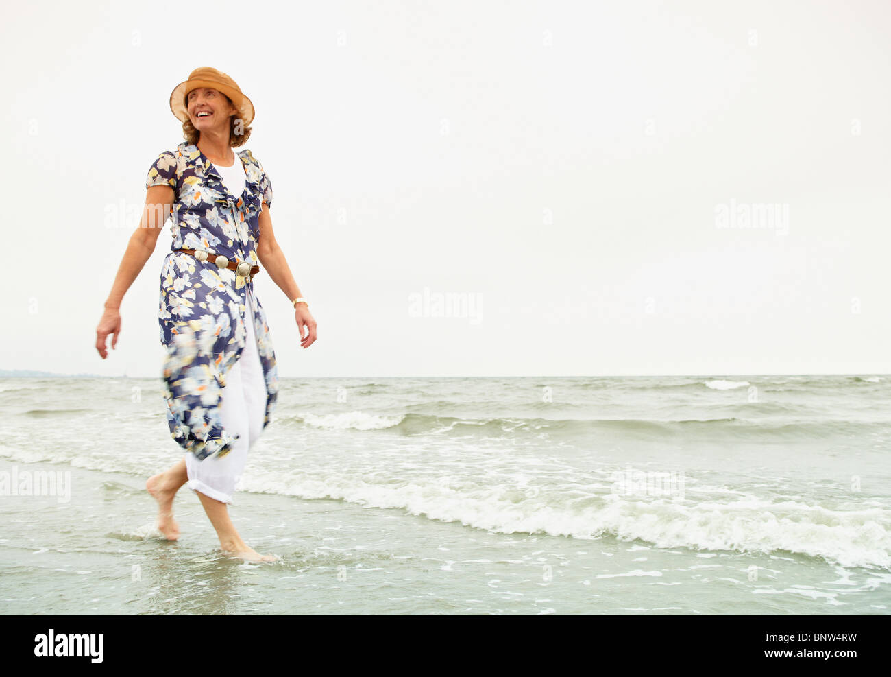 Donna di camminare sulla spiaggia Foto Stock