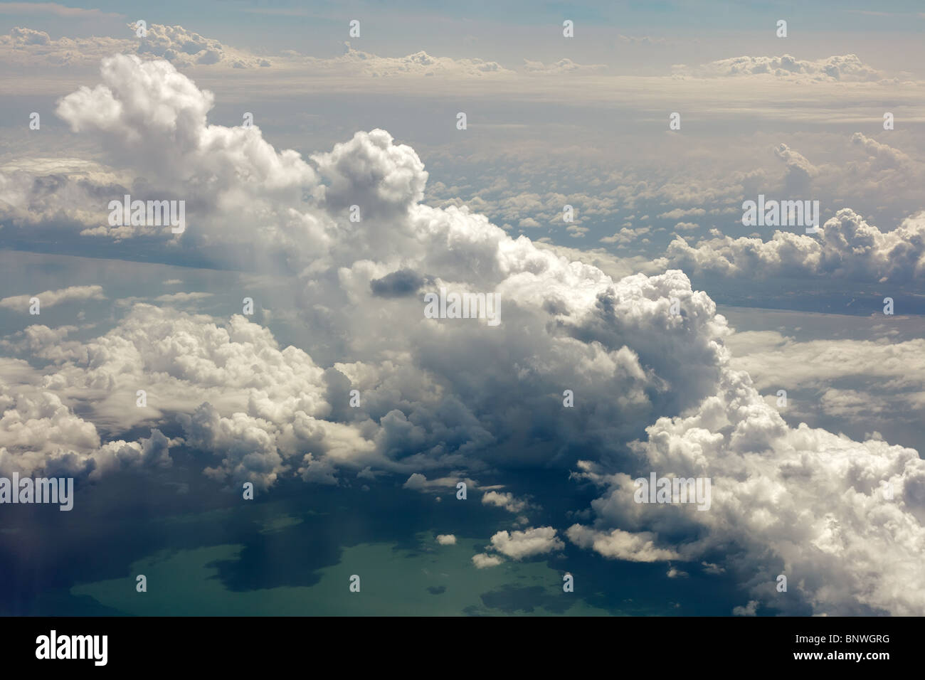 Vista su cloudscape e mare dalla finestra di aeroplano Foto Stock