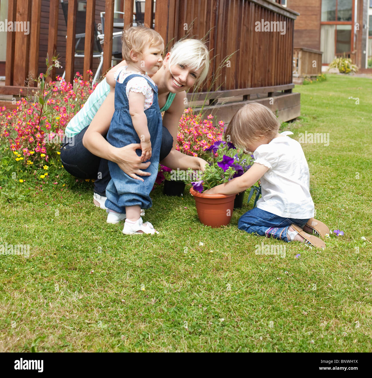 Donna sorridente con due bambini in giardino Foto Stock